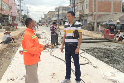 刘家好(右)在修路现场与工人交谈