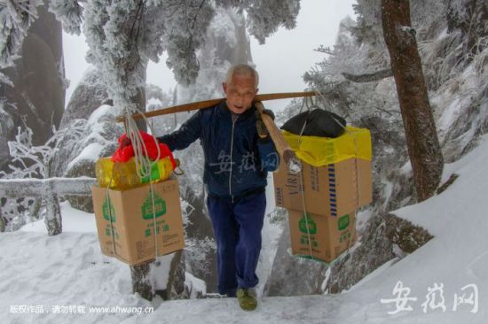 黄山风景区近日普降大雪，挑山工方银善冒雪向山上送货。像他这样的挑山工，景区还有139个。孙俊摄