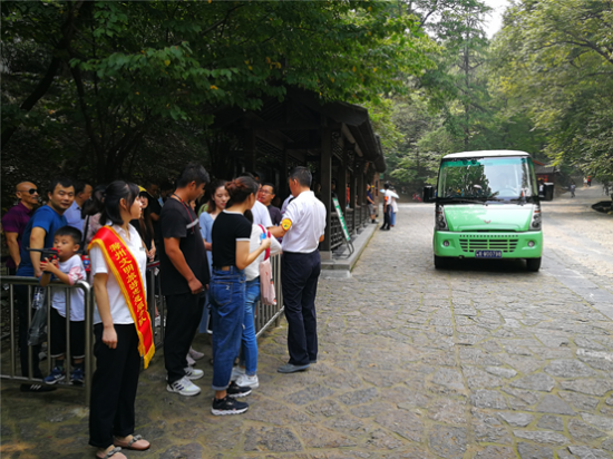 文明旅游志愿者在观光车驿站引导游客有序乘车