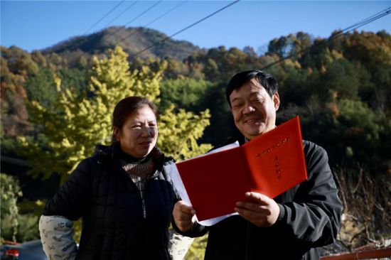 唐少平（左）查看自家的“旌德县生态资源受益权证”。人民网记者 陶涛摄