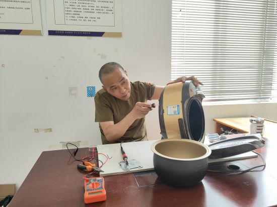 刘家鸿在小区便民服务点义务为群众修理电饭锅