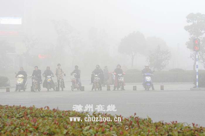 市民在雾霾中等待绿灯通行